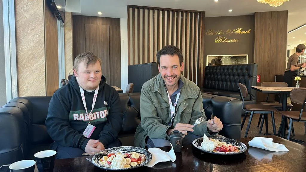 A Focus participant and a support worker having lunch together at a local café.
