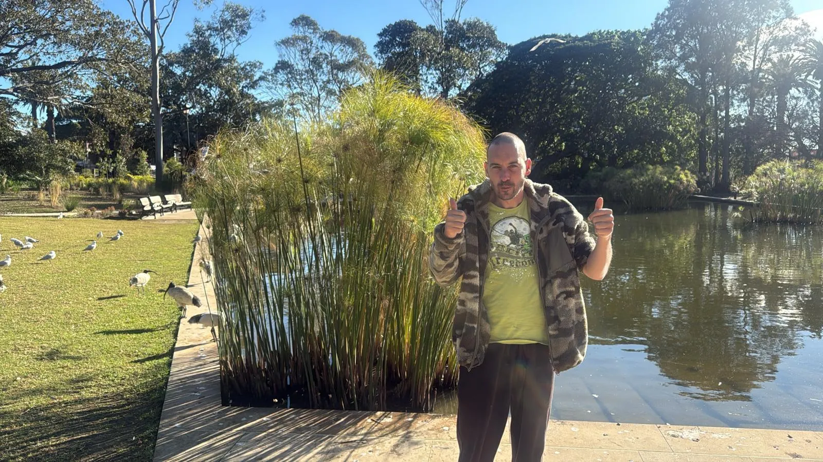 A Focus participant giving two thumbs up beside a pond in a Sydney park on a clear winter morning.